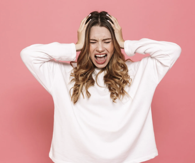 Junge Frau mit langen, blonden Haaren lächelt in einem hellen Raum.