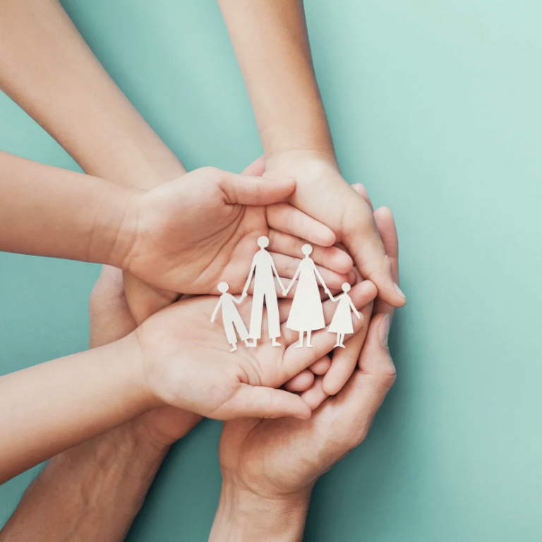 Verschiedene Hände halten Figuren einer Familie symbolisch.