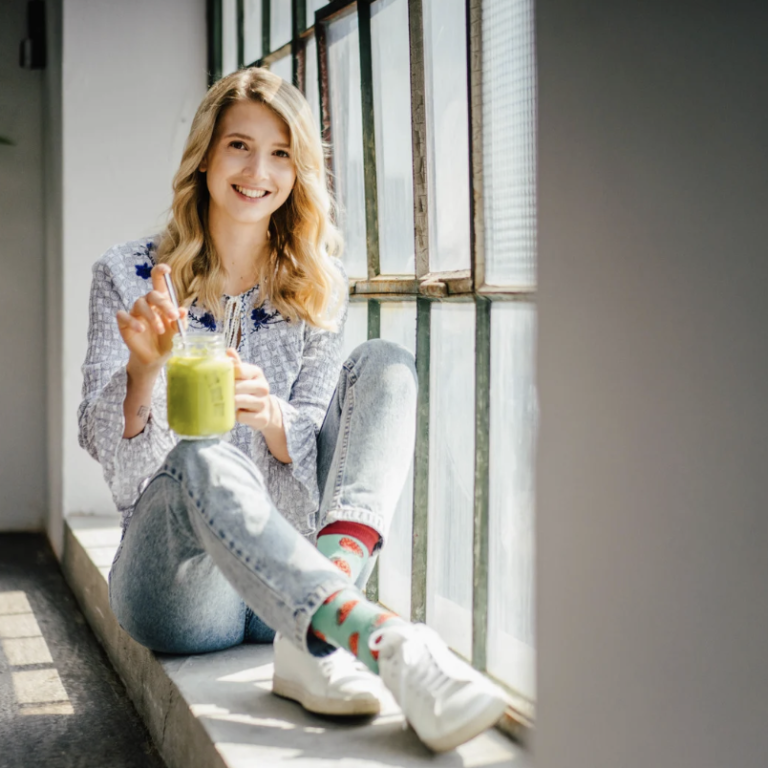 Persönliches Coaching Frau sitzt auf Fensterbank und hält ein Glas in der Hand